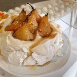 Roasted pear pavlova topped with whole caramelized pears and caramel
