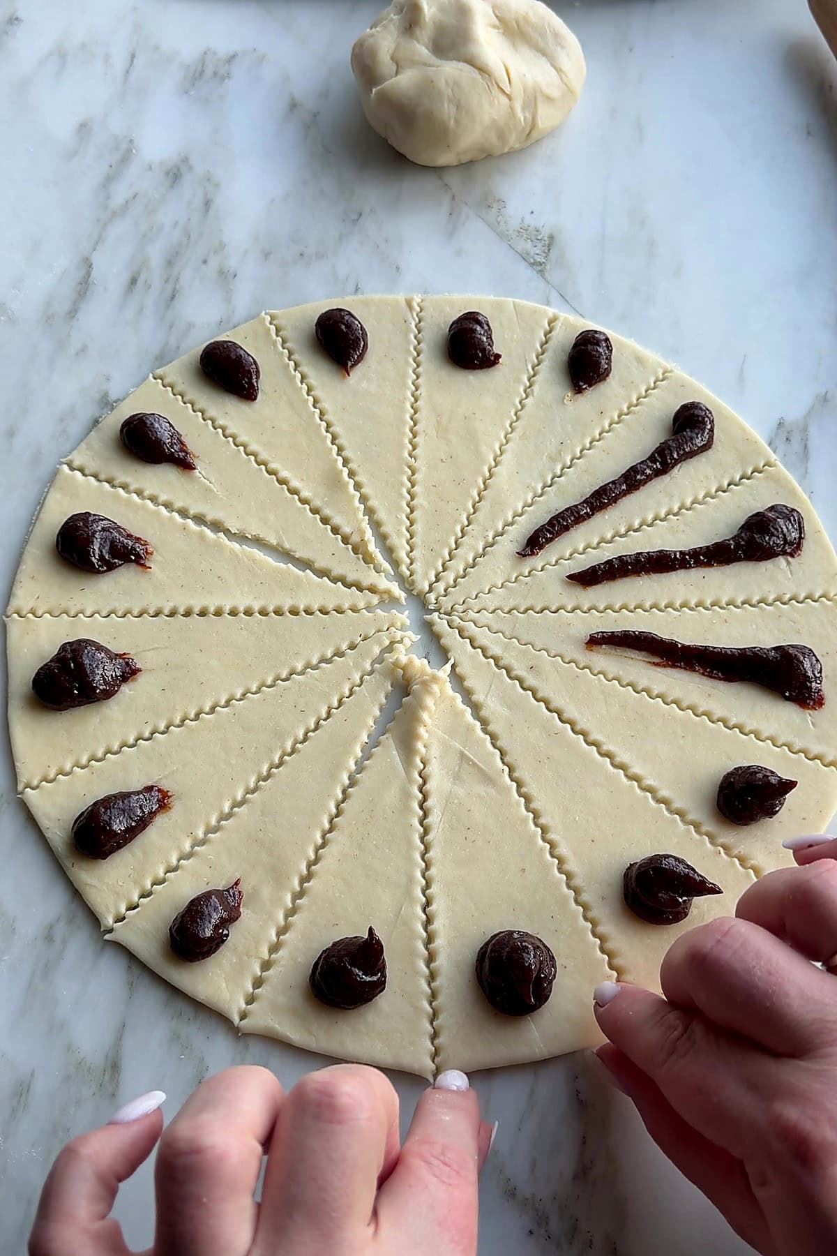 Rogaliki dough round cut into wedges with plum butter piped on each one