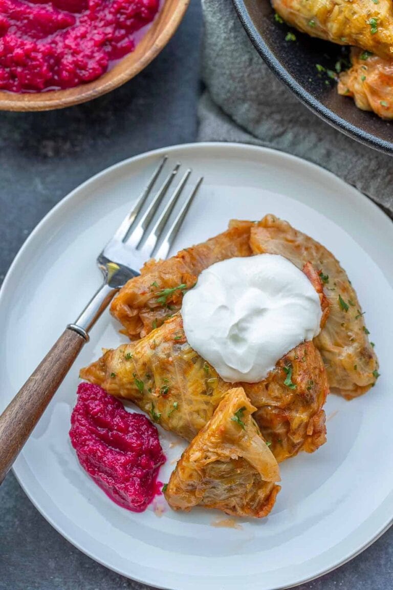 Cabbage rolls with sour cream and beet horseradish on a white plate