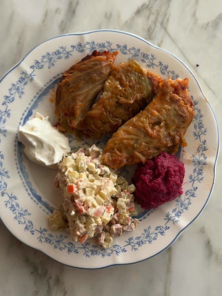Chrain, beet and horseradish relish, on a holiday plate with cabbage rolls, Olivier salad and sour cream