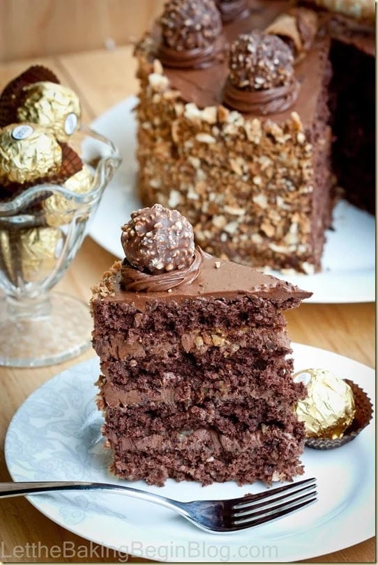 Slice of Ferrero Rocher cake showing four hazelnut sponge layers with Nutella chocolate buttercream, next to Ferrero Rocher candies