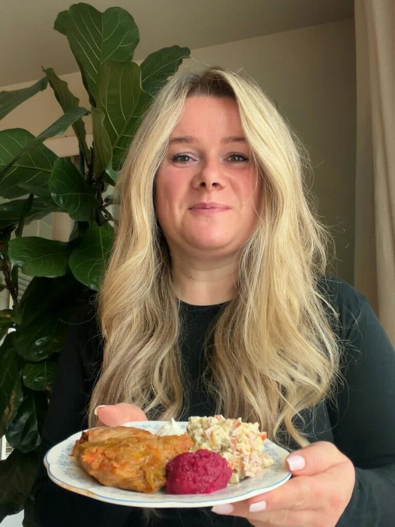 Marina holding a plate of cabbage rolls, Olivier salad and hrin, Ukrainian beet horseradish
