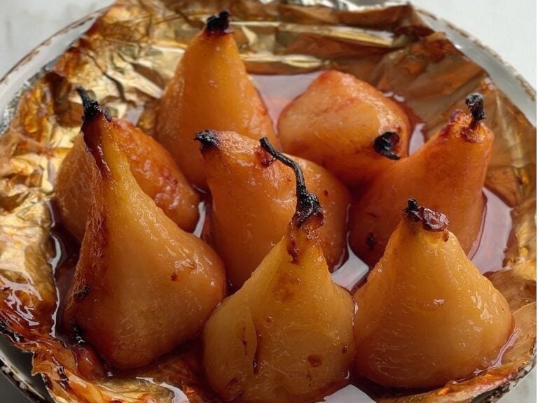 Whole air fryer pears in caramel syrup in a foil-lined dish