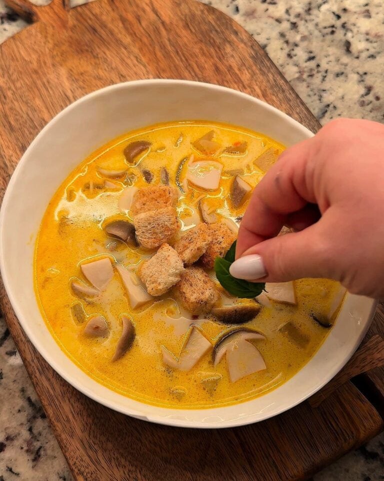 Bowl of creamy mushroom soup with porcini mushrooms and croutons on a wooden board